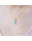 18K yellow gold emerald-cut emerald pendant with diamond halo on a delicate chain.