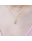 18K yellow gold emerald-cut emerald pendant with diamond halo on a delicate chain.