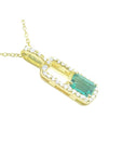 An emerald-cut Colombian emerald pendant with a halo of natural diamonds, handcrafted in 18K yellow gold.