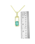 18K yellow gold emerald-cut emerald and diamond halo pendant necklace, shown with ruler for size.