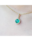 Round cut Colombian emerald pendant with halo diamonds on a 14K gold chain.