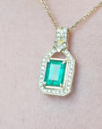 Gold pendant with square natural emerald and diamonds on a pink skin background