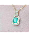Gold pendant with square natural emerald and diamonds on a pink skin background
