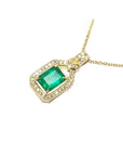 A 18k yellow gold necklace with an emerald and diamond pendant on a white background