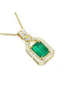 A 18k yellow gold emerald pendant with natural accent diamonds surrounding the square gemstone, toside view.