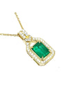 A 18k yellow gold emerald pendant with natural accent diamonds surrounding the square gemstone, toside view.