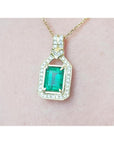 Natural colombian emerald pendant with diamond accents on a gold chain against a pink skin background