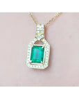 Natural colombian emerald pendant with diamond accents on a gold chain against a pink skin background