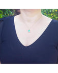 Emerald and diamond pendant in 18K yellow gold, worn on a woman's neck.