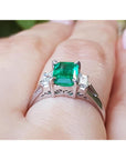 Emerald-cut emerald platinum ring held on a hand.