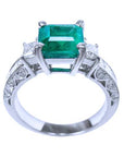 This colombian emerald ring displays its lateral position, where top setting, gallery and decorated band profile are visibles/