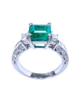 This colombian emerald ring displays its lateral position, where top setting, gallery and decorated band profile are visibles/