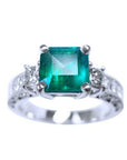 A real colombian emerald ring with side princess cut diamonds on front position displaying top and sideways band profile.