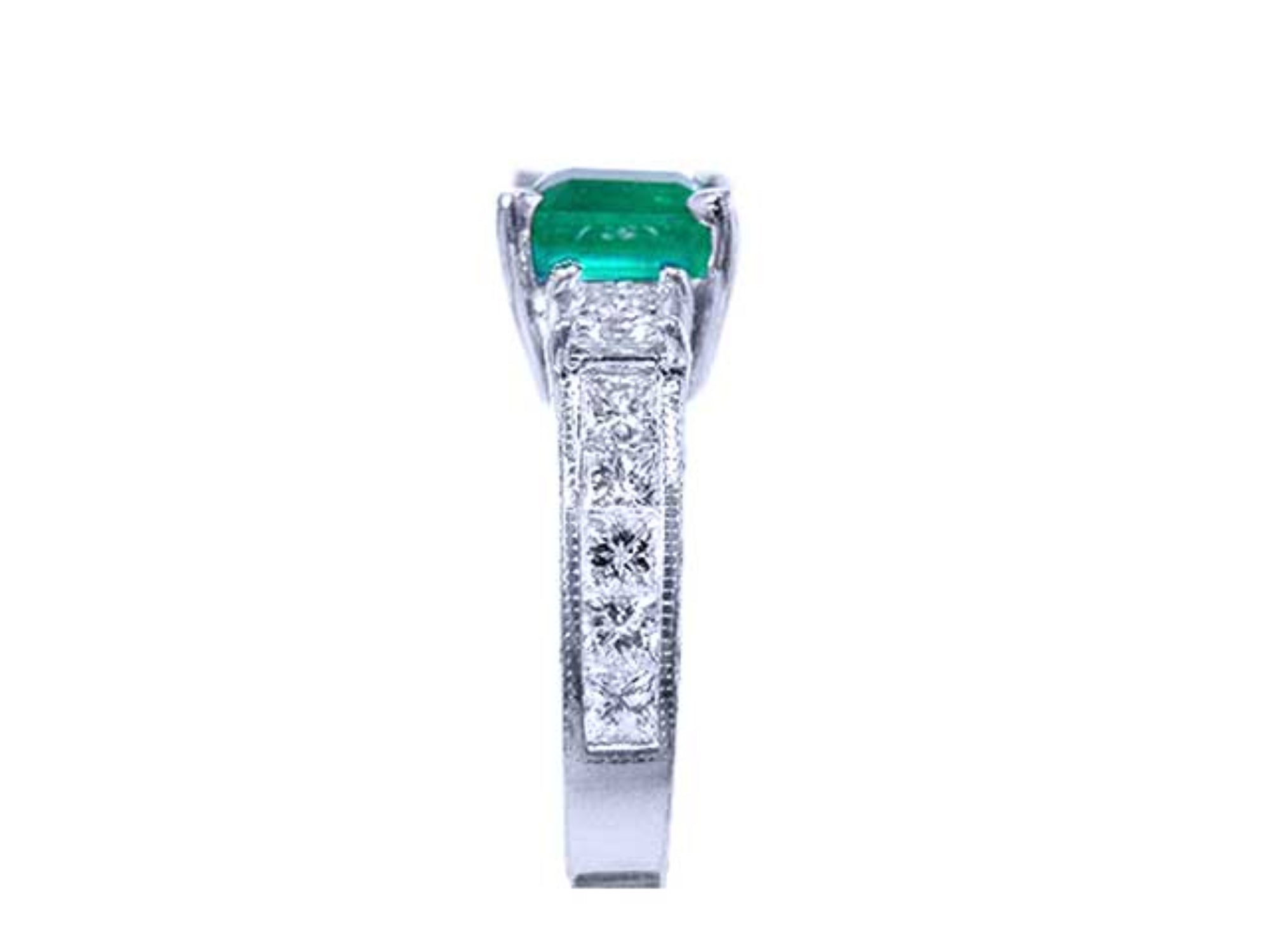 The sparkling greenfire of this Colombian emerald ring on top and the side vibrant princess cut diamonds on the band are visibles.