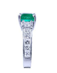 The sparkling greenfire of this Colombian emerald ring on top and the side vibrant princess cut diamonds on the band are visibles.