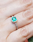 A square natural colombian emerald ring on a hand.