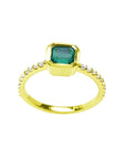 Bezel-set emerald ring with accent diamonds on a 14K yellow gold band.