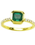 A topside view of a natural colombian emerald ring with diamond accents on a white background.