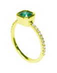 The top bezel setting and side band with diamonds perspective are visibles in this yellow gold emerald ring.