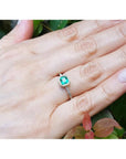 Bezel-set emerald ring with accent diamonds on a 14K yellow gold band, worn on a hand.