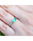 14K yellow gold east-west emerald ring with a bezel-set rectangular emerald and diamond band.