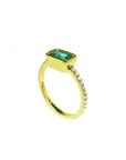 Side profile of a yellow gold emerald ring on a white background.