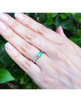 East-west emerald-cut Colombian emerald ring, bezel set in 14K yellow gold with diamond accents.