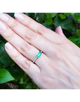 East-west emerald-cut Colombian emerald ring, bezel set in 14K yellow gold with diamond accents.