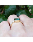14K yellow gold east-west emerald ring, bezel set rectangular emerald with accent diamonds on band.