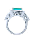 18K white gold ring with a rectangular emerald, diamond halo, and intricate filigree side details.