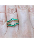 An emerald ring guard made of 14k yellow gold on a finger.