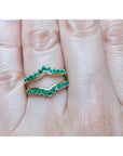 An emerald ring guard made of 14k yellow gold on a finger.
