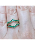 An emerald ring guard made of 14k yellow gold on a finger.