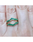 An emerald ring guard made of 14k yellow gold on a finger.
