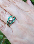 Hand wearing a ring guard with an inserted solitaire diamond ring against a blurred green background.