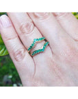 14K yellow gold emerald ring guard with 22 round-cut Colombian emeralds, worn on a finger.