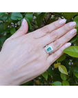 1.01 carat emerald ring with double halo diamonds and matching band in 14K white gold on a hand.