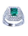 An emerald-cut colombian emerald encircled in double halo diamond ring in white gold.