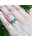 1.27 carat Colombian emerald ring with halo diamonds and split shank in 14K yellow gold on a hand.