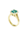 1.27 carat Colombian emerald ring in 14K yellow gold with halo diamonds and a split shank.