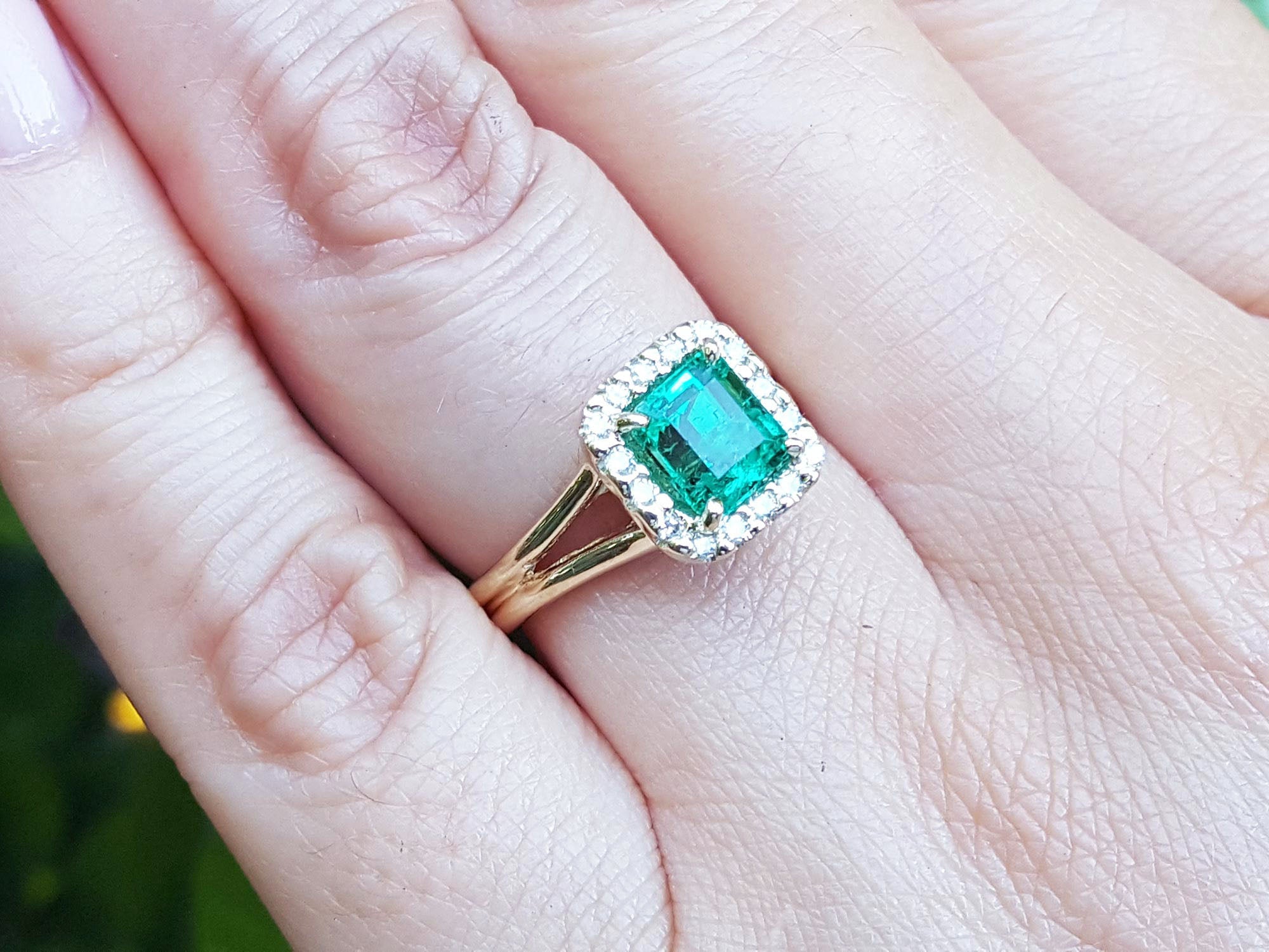 Square emerald and halo diamond ring in yellow gold on a person's hand