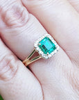 Square emerald and halo diamond ring in yellow gold on a person's hand