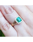 Square emerald and halo diamond ring in yellow gold on a person's hand