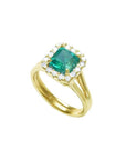 1.27 carat Colombian emerald ring in 14K yellow gold with halo diamonds and a split shank.