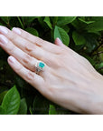 Emerald-cut emerald ring with double diamond halo and matching band in 14K yellow gold on a hand.