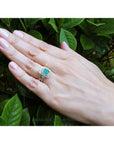 Emerald-cut emerald ring with double diamond halo and matching band in 14K yellow gold on a hand.