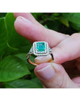 1.31 ct emerald-cut emerald ring with double diamond halo and 14K yellow gold band.
