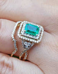 Gold ring with a colombian emerald surrounded by a double halo diamond on a hand.