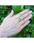 Men's 18K yellow gold ring with a rectangular emerald and diamond accents, worn on a hand.