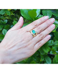 Men's 18K yellow gold ring with a rectangular emerald and diamond accents, worn on a hand.